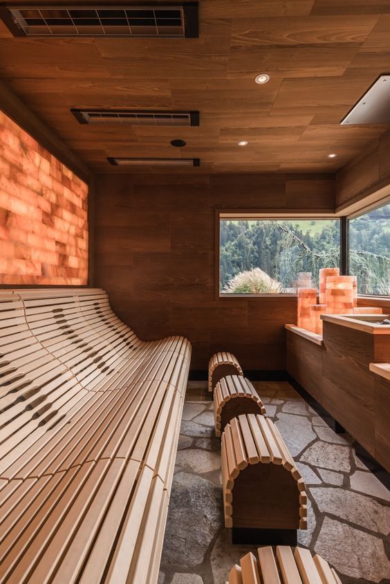 Cedar sauna with a backlit stone wall and contoured benches