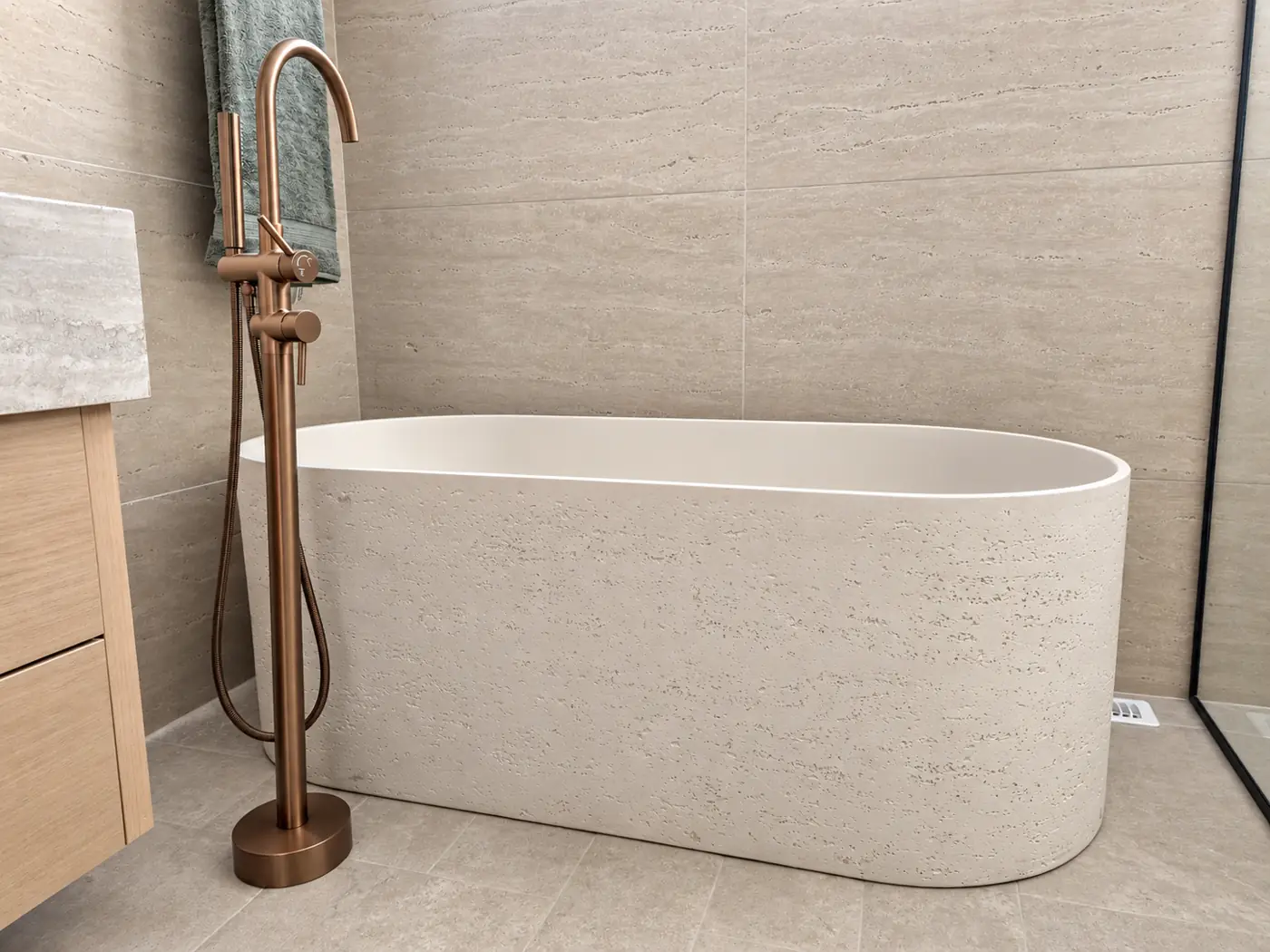 Travertine freestanding tub with a bronze floor-mounted filler